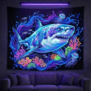 May include: Black tapestry featuring a vibrant, glowing shark illustration. The artwork showcases a detailed shark with blue, purple, and white hues, surrounded by coral, jellyfish, and fish. The design is set against a dark background.