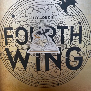 K&ouml;nnte beinhalten: Ein goldener Buchumschlag mit einer Schwarzwei&szlig;illustration eines Drachen und eines Buches mit dem Text "FLY...OR DIE" darauf. Der Titel des Buches lautet "FORTH WING" und der Autor ist "REBECCA YARROS".