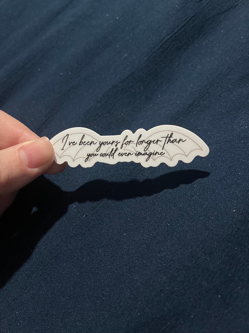 May include: White sticker with black text and a pair of bat wings. The text reads "I've been yours for longer than you could even imagine."