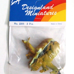 May include: A package of Designland Miniatures, containing two miniature figurines. The figurines are a mix of yellow and brown, with white spots. The packaging has a blue header with the brand name and a rainbow design.