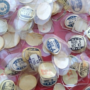 May include: A collection of vintage watch crystals in various sizes and shapes, some with labels including brand names like Bulova and KK, and numbers like 106/2, 84, and 170.