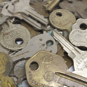 May include: A close-up of a pile of vintage keys, some with the words "Yale" and "Good's Mfg. Co." on them. The keys are made of metal and have a variety of shapes and sizes.