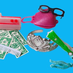May include: A collection of miniature toys on a blue background. Includes a pink radio, a pink purse with black glasses, a silver tiara, a green flashlight, a comb, and toy dollar bills.