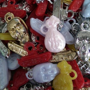 May include: A collection of colorful plastic charms, including a tank, a bag of money, a skull, and a gun. The charms are made of various colors, including red, yellow, blue, and silver.
