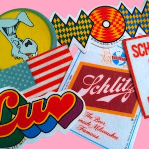 May include: A collection of vintage stickers with various designs and text. Includes a cartoon donkey in a yellow circle, a red and white striped pattern, and a sticker that says "SCHOOL IS A DRAG".