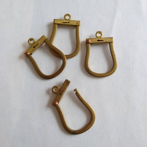 May include: Four gold-toned metal purse frame clasps with a small, round, copper-colored accent on each. The clasps are designed to be attached to a purse or bag.