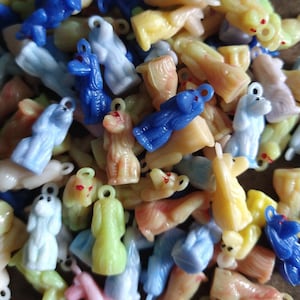 May include: A collection of colorful plastic charms in various shapes, including animals, stars, and hearts. The charms are strung on a chain or cord, and some have a metal ring for attaching to a keychain or bracelet.