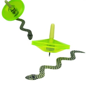 May include: Two green plastic spinning tops with a snake design. The tops are shaped like a disc with a pointed tip. The snake design is black and white.