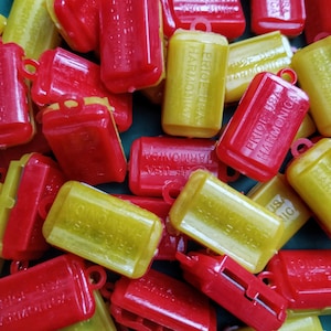 May include: A close-up of a pile of red and yellow plastic harmonicas. The harmonicas have the words "Price USA Harmonica" printed on them.