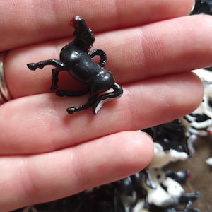 May include: A black plastic horse figurine with a red nose. The horse is standing on its hind legs with its front legs raised. The figurine is about 2 inches tall.