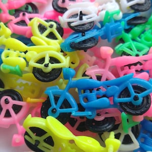 May include: A collection of colorful toy motorcycles in shades of pink, yellow, blue, and green. The miniature bikes have black wheels and are made of plastic. The image is a close-up, showing the bikes overlapping each other.