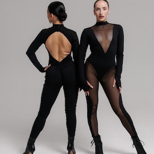Op de afbeelding: Twee zwarte jumpsuits. Eén heeft een sleutelgatenrug en lange mouwen. De andere heeft een doorschijnende halslijn en panelen op de benen. Beide outfits worden gedragen met zwarte laarzen met hakken. De achtergrond is effen lichtgrijs.