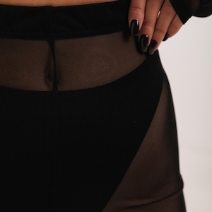 May include: Black mesh leggings with a high waist and a wide waistband. The leggings are sheer and have a black lining.