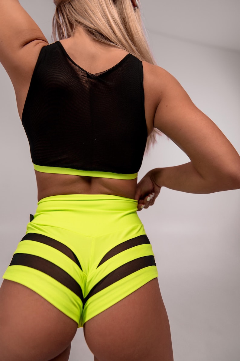 May include: Neon yellow athletic shorts with black mesh panels. The shorts have a high waist and a fitted silhouette.
