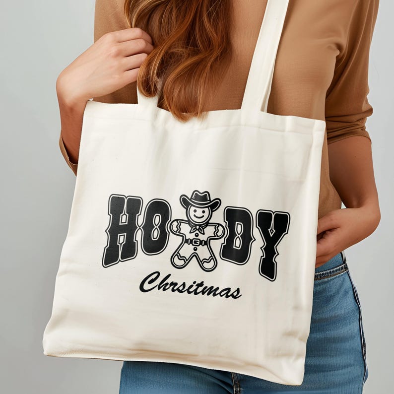 May include: A white canvas tote bag with black text that reads "Howdy Christmas" and a gingerbread man wearing a cowboy hat.