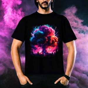 Puede incluir: Una camiseta negra con un gráfico colorido de una explosión en forma de hongo. El gráfico es vibrante y detallado, con tonos de rosa, azul y morado.