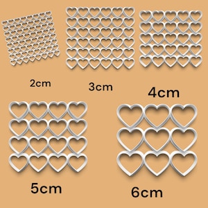 May include: White heart-shaped stencils in various sizes, from 2 cm to 6 cm. The stencils are arranged in a grid pattern, with each size having its own grid.