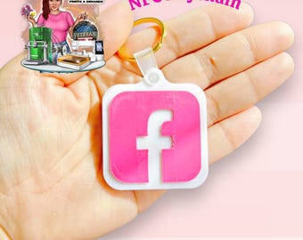 May include: A white and pink NFC keychain with the Facebook logo. The keychain has a gold-colored ring and a clear plastic connector. The text "NFC Keychain" is above the keychain. The background is a light pink color.
