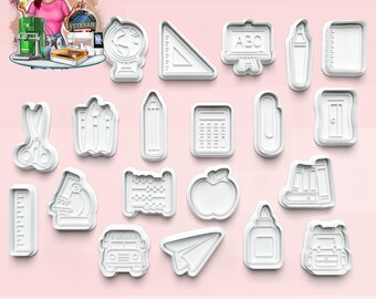 May include: A collection of white plastic cookie cutters in various school-themed shapes, including a globe, ruler, pencil, calculator, apple, and backpack. The cutters are arranged on a light pink surface.