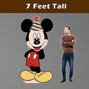 Puede incluir: Un gran recorte de dibujos animados de Mickey Mouse con un gorro de fiesta, de pie junto a un hombre. El recorte mide 213 cm de altura. Mickey Mouse lleva una camisa roja, zapatos amarillos y pantalones cortos negros. El hombre lleva un su&eacute;ter marr&oacute;n y vaqueros azules.