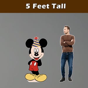 Puede incluir: Un recorte de Mickey Mouse de 152 cm de altura con un gorro de fiesta, junto a un hombre. Mickey Mouse lleva su atuendo cl&aacute;sico con pantalones cortos rojos, zapatos amarillos y guantes blancos. El texto "5 Feet Tall" est&aacute; arriba.