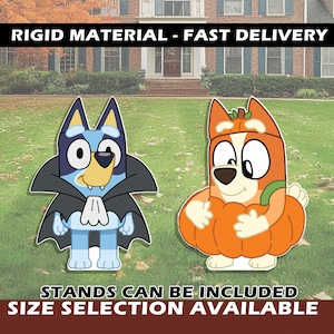 May include: Two rigid yard signs featuring cartoon dog characters. One blue dog wears a black vampire cape with a white cravat. The other orange dog wears a pumpkin costume with a green stem. Text reads: RIGID MATERIAL - FAST DELIVERY, STANDS CAN BE INCLUDED, SIZE SELECTION AVAILABLE.