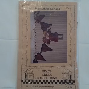 May include: A craft pattern for a Sweet Annie Garland, featuring a 7 1/2 inch doll with a gingerbread recipe. The pattern is from Peace Creek Collections and is number 63.
