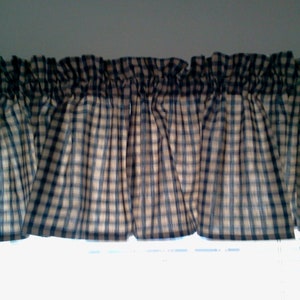 May include: A valance with a checkered pattern in tan and blue. The valance is made of fabric and has a gathered look.