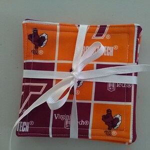 May include: Set of four orange and maroon fabric coasters with a Virginia Tech logo and a turkey mascot. The coasters are tied together with a white ribbon.
