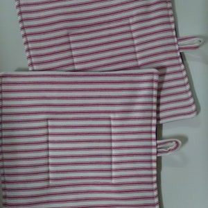 May include: Two white and pink striped pot holders with a pocket on each. The pot holders have a loop for hanging.