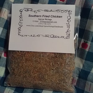 May include: A clear plastic bag filled with a brown spice blend, labeled "Southern Fried Chicken" with the seller's information. The bag is set against a blue and white checkered fabric with red apple designs.