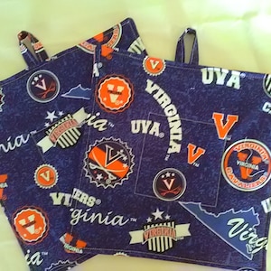May include: Three blue and orange pot holders with the University of Virginia logo and the words "Virginia Cavaliers" and "UVA".