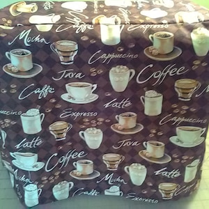 May include: A brown fabric coffee maker cover with a repeating pattern of coffee cups, coffee beans, and the words "Mocha", "Expresso", "Cappuccino", "Java", "Caffe", "Latte", and "Coffee".