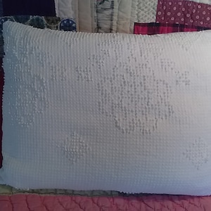 May include: A white pillow with a textured surface and a snowflake design. The pillow is made of a soft, fluffy material.