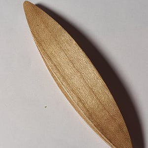以下が含まれることがあります： 木製の明るい茶色のボート型のオブジェクトで、表面はテクスチャ加工されています。 オブジェクトは細長く、両端が尖っています。 木目は見え、オブジェクトは手作りであるようです。