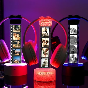 May include: Three illuminated headphone displays with personalized photo strips. The headphones are red, pink, and black, with the photo strips displaying black and white images. The bases of the displays are red and black.