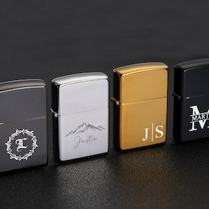 May include: Four personalized lighters in black, silver, gold, and black. Each lighter features a unique design: a letter within a wreath, a mountain scene with a name, initials, and a monogram with a name and Roman numerals.