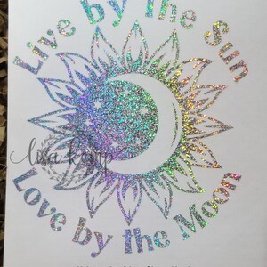 Peut inclure: Un autocollant en vinyle paillet&eacute; argent&eacute; holographique avec le texte "Live by the sun, Love by the moon". L'autocollant pr&eacute;sente un motif de soleil et de lune avec une forme de croissant de lune.