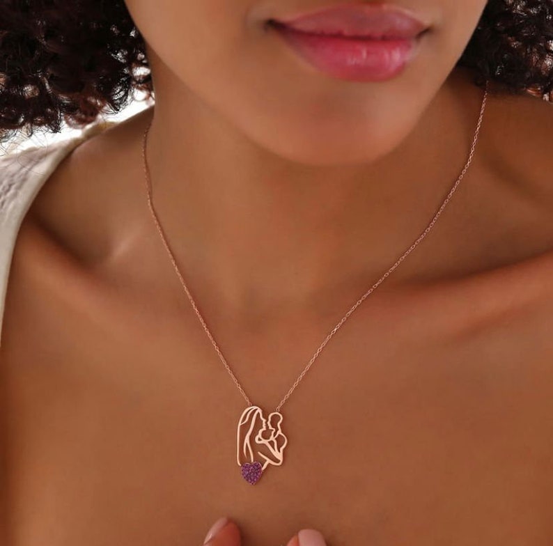 This necklace portrays a mother holding her baby under a red heart. Symbolizing love and maternal connection, it's a meaningful accessory suitable for any occasion