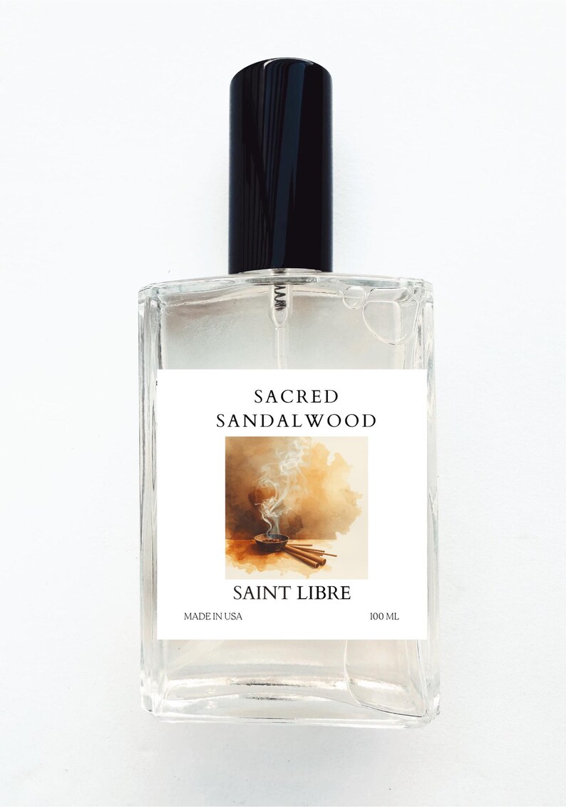 May include: A clear glass perfume bottle with a black cap. The label reads "Sacred Sandalwood" and "Saint Libre." The label features an illustration of incense and sticks. The bottle contains 100 mL of product and is made in the USA.