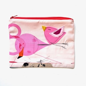 May include: Pink zippered pouch with a pink flamingo and a pink bird with a yellow beak. The background is a light pink with black lines.