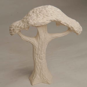 May include: A cream-colored ceramic tree sculpture. The tree has a textured trunk with a knot detail and a wide, textured canopy. The sculpture is a decorative item, likely for home decor.