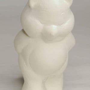 May include: A white, ceramic bear figurine with a rounded body and small ears. The bear is standing upright with its arms at its sides. The figurine has a smooth, matte finish and is suitable for home decor.