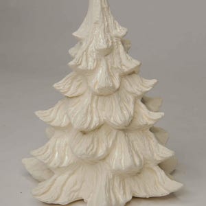 May include: A solid off-white, unpainted ceramic figurine shaped like a coniferous tree. The surface features detailed, molded textures that mimic the layered, pointed needles and branches of a pine tree, creating a realistic, textured appearance.