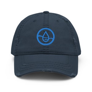 Peut inclure: Une casquette de baseball en denim bleu marine usée avec un logo brodé bleu d'une goutte d'eau dans un cercle.