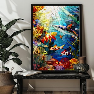 May include: A framed stained glass artwork depicting an underwater scene. The artwork features colorful fish, coral, and a shark against a blue and yellow background. The frame is black.
