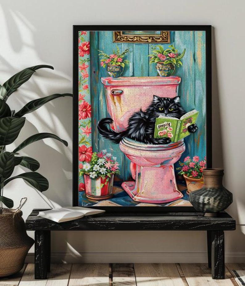 May include: A black cat sitting on a pink toilet with a book titled "Poo-ping" in its paws. The cat is in a bathroom with floral decorations and a blue wall.