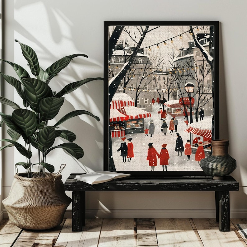 Puede incluir: Una ilustraci&oacute;n de una escena de calle invernal en una ciudad europea nevada, con edificios de techos rojos, un mercado navide&ntilde;o y gente caminando. La ilustraci&oacute;n est&aacute; enmarcada en negro y colgada en una pared sobre un banco de madera negro.