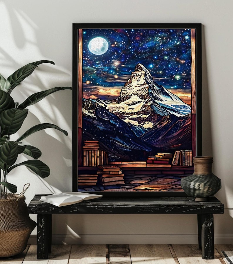 May include: A framed print of a mountain range with a full moon and stars in the night sky. The mountain range is surrounded by a stack of books.