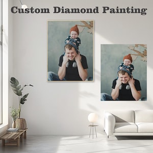 May include: Two diamond painting kits featuring a father and child. The father is holding the child on his shoulders. The child is wearing a brown hat. The background is a light blue color.